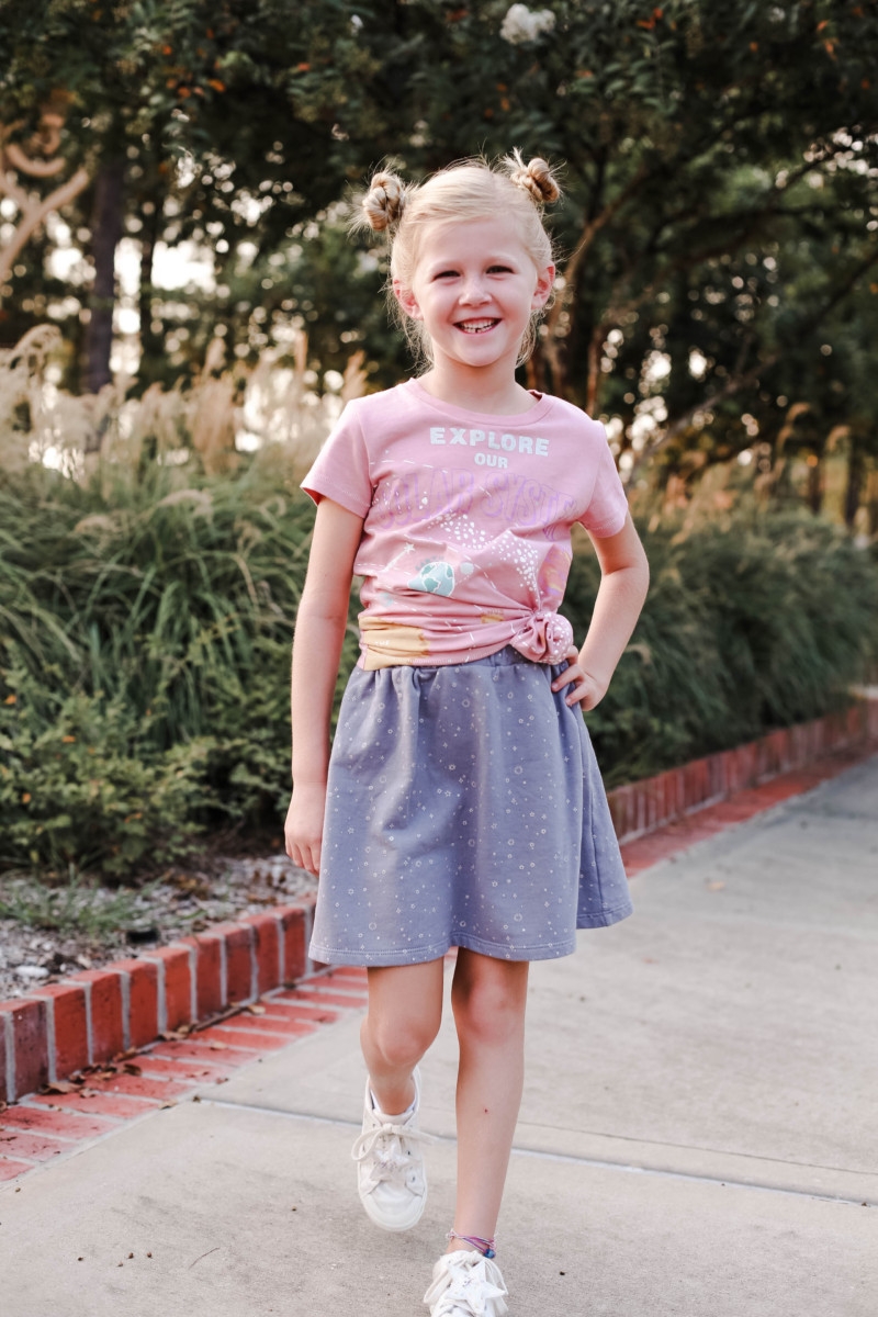 girls back to school outfit | How to Get to School on Time: 7 Easy Ways by popular Houston blog, Haute and Humid: image of a girl standing outside and wearing a Peek Aren't You Curious Solar System Graphic Tee, Peek Aren't You Curious Violet Skirt.