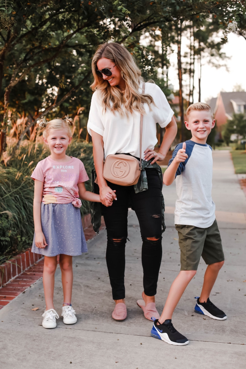 school on time | How to Get to School on Time: 7 Easy Ways by popular Houston blog, Haute and Humid: image of a mom and two kids standing outside and wearing a Peek Aren't You Curious Solar System Graphic Tee, Peek Aren't You Curious Violet Skirt, All in Favor Button Back Top, Madewell 9-Inch High Waist Skinny Jeans, Caslon Metallic Stitch Utility Jacket, Gucci Soho Disco Leather Bag, Tucker and Tate Baseball T-Shirt, Tucker and Tate Knit Shorts, and Nike Free Run 5.0 Sneaker.