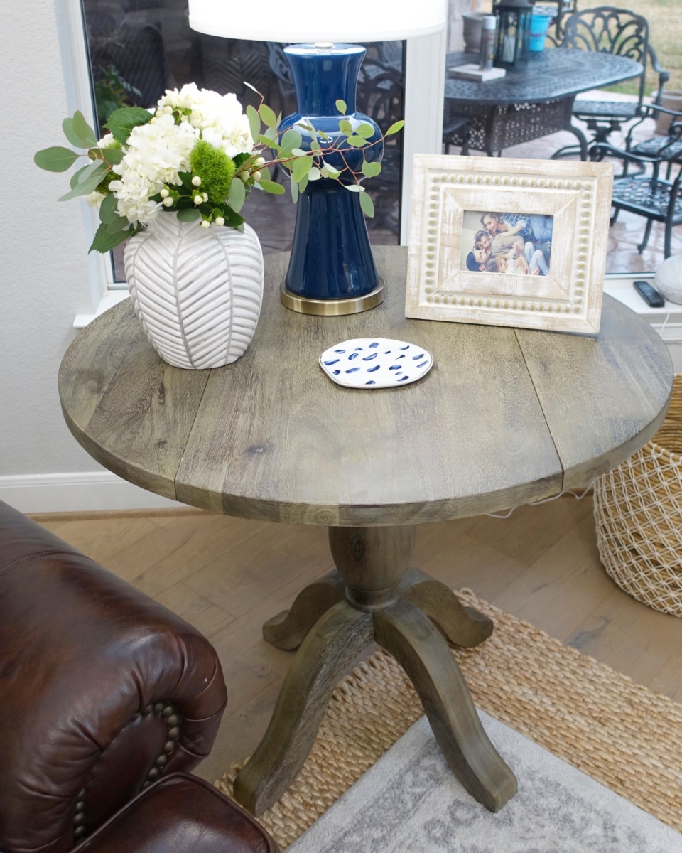 end table | Living Room Makeover by popular Houston lifestyle blog, Haute and Humid: image of a remodeled living room with coffee table containing a white flower vase, wood picture frame, and blue lamp.
