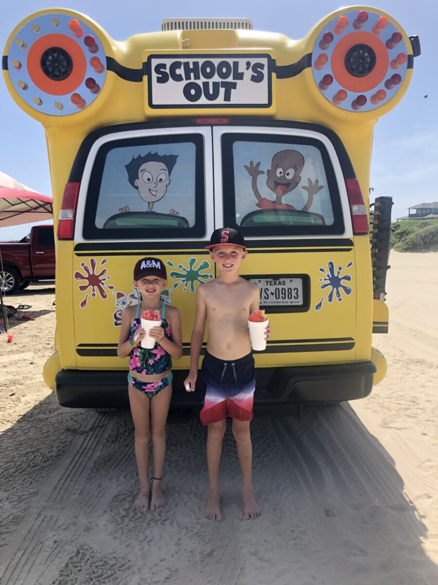 galveston beaches | Galveston Travel Guide by popular Houston travel blog, Haute and Humid: image of two kids wearing swimsuits and eating snow cones on a Galveston Texas beach. 