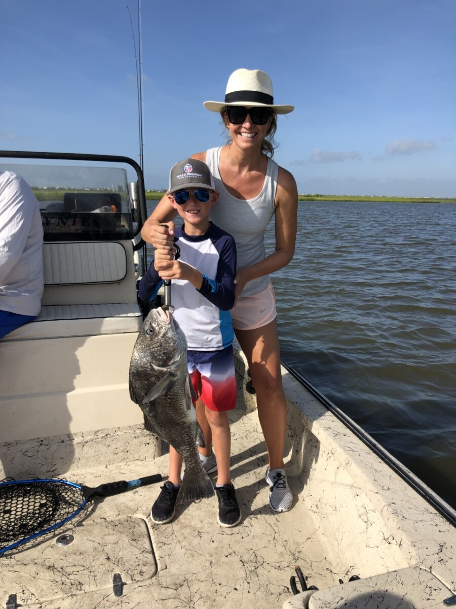 fishing in galveston | Galveston Travel Guide by popular Houston travel blog, Haute and Humid: image of a mom and her son holding a large silver fish on a boat in Galveston Texas. 