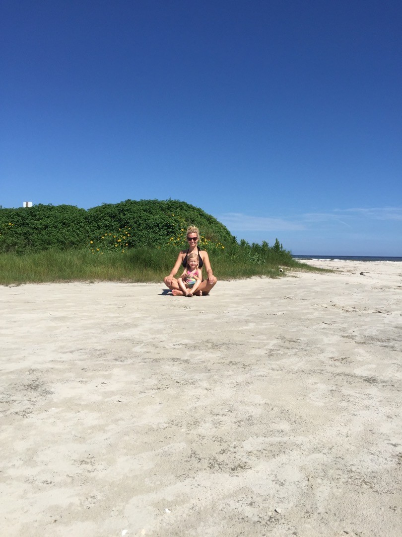 galveston beaches | Galveston Travel Guide by popular Houston travel blog, Haute and Humid: image of a woman and her daughter sitting on a sandy beach in Galveston, Texas. 