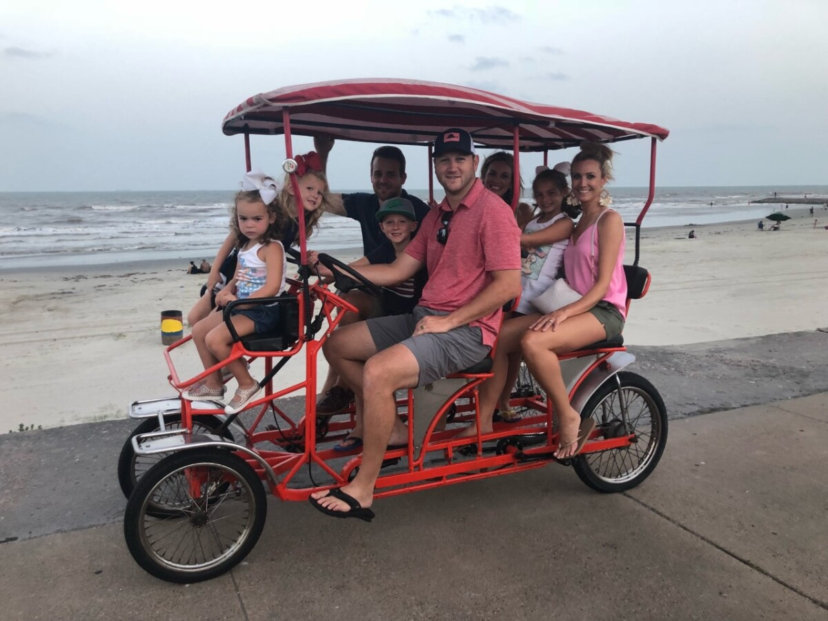 galveston bike rentals | Galveston Travel Guide by popular Houston travel blog, Haute and Humid: image of a family riding a bike cart on a Galveston, Texas beach. 