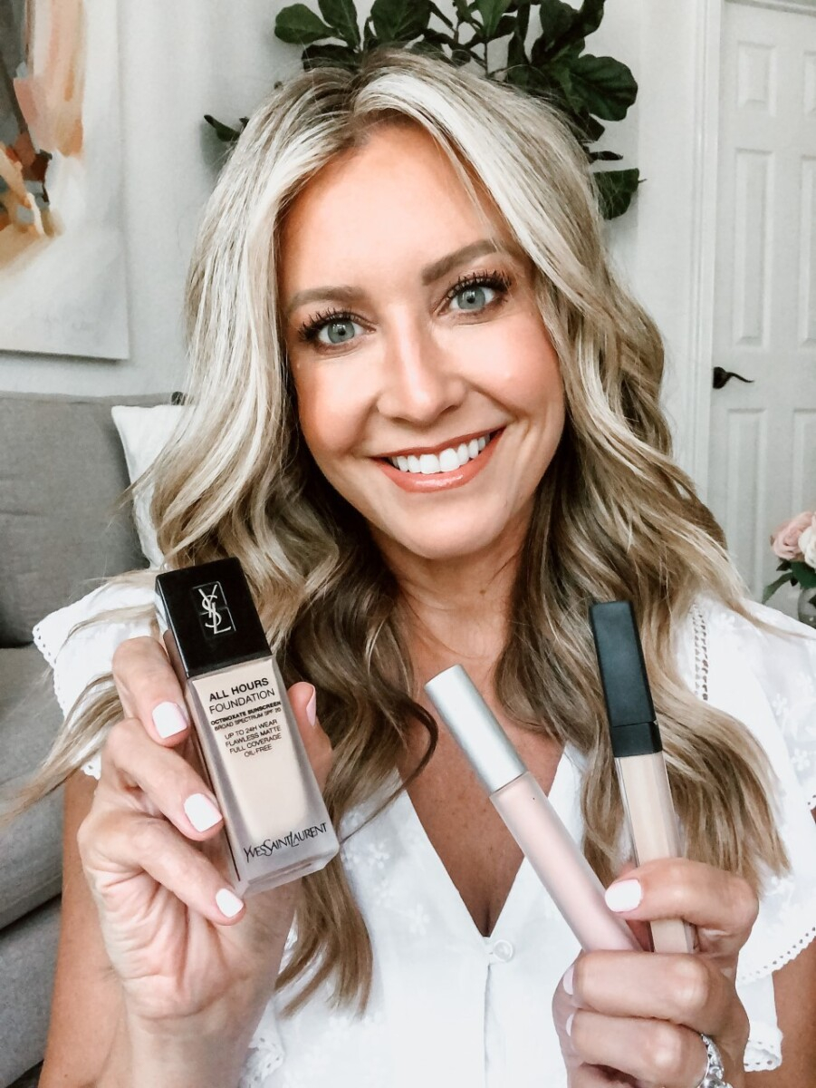 Sweat Proof Makeup Tips | Sweat Proof Makeup by popular Houston beauty blog, Haute and Humid: image of a woman holding a bottle of YSL all hours foundation, HOURGLASS Veil Mineral Primer, and NARS Pro Prime Smudgeproof Eyeshadow Base.