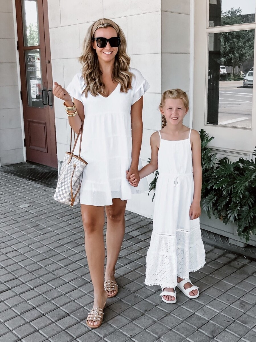 white summer dresses | White Summer Dresses by popular Houston fashion blog, Haute and Humid: image of a mom and daughter standing together and holding hands outside and wearing a Nordstrom SOCIALITE Tiered Babydoll Dress, Nordstrom MARC FISHER LTD Pava Slide Sandal, Amazon zeroUV - Retro Oversized Square Sunglasses, Budha Girl GOLD ALL WEATHER BANGLES, Amazon Funtopia Knotted Headband, and Target Cat & Jack Girls' Eyelet Maxi Dress.