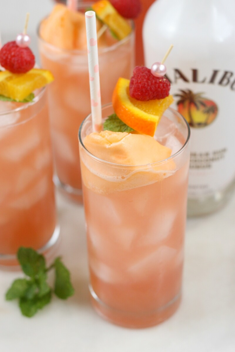 pitcher drinks | Pitcher Cocktails by popular Houston lifestyle blog, Haute and Humid: image of a pink bikini drink in a tall clear glass with a pink and white polka dot straw next to a bottle of Malibu rum. 