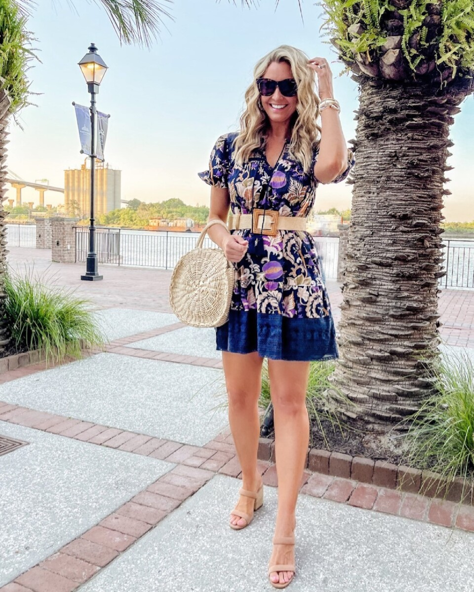 Girlfriends Guide To Savannah | Savannah Georgia Travel Guide by popular Houston travel blog, Haute and Humid: image of a woman standing outside and wearing a purple mini dress, woven waist belt, tan suede block heel sandals, and holding a woven circular handbag. 